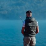 Young man with fishing rod by the river