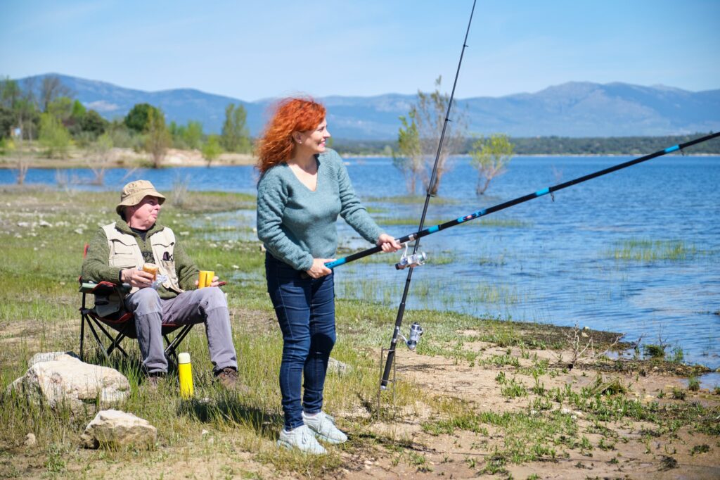 A man and a woman are fishing in a lake
