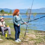 A man and a woman are fishing in a lake